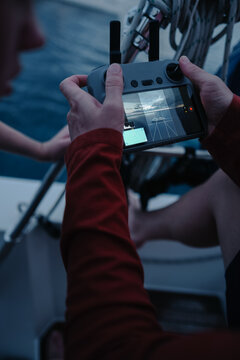 Man's hands holding drone controller on boat deck flying UAV whi