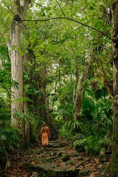 Long-haired woman in brown polka dot dress walking through wild