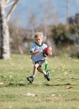young boy running with a football in flag football