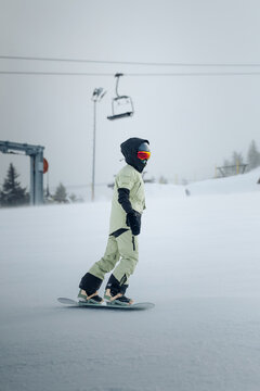 Snowboarder Riding Across Snowy Slope on Overcast Winter Day