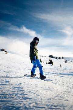 Snowboarder gliding across alpine landscape on clear winter day