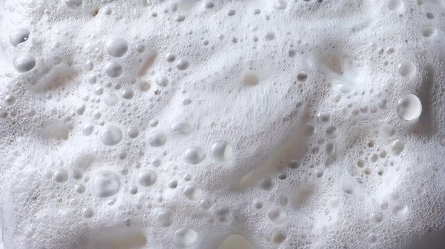 Foamy bubbles create a textured surface in a close-up view of white liquid