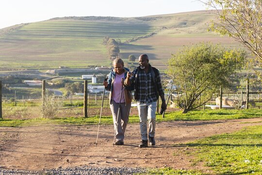 Senior african american couple with backpacks walking in sunny nature
