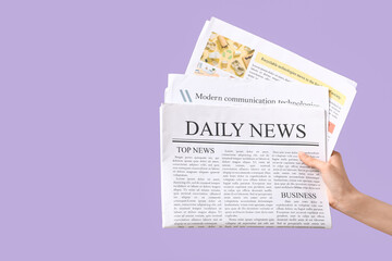 Naklejka premium Female hand with newspapers on lilac background