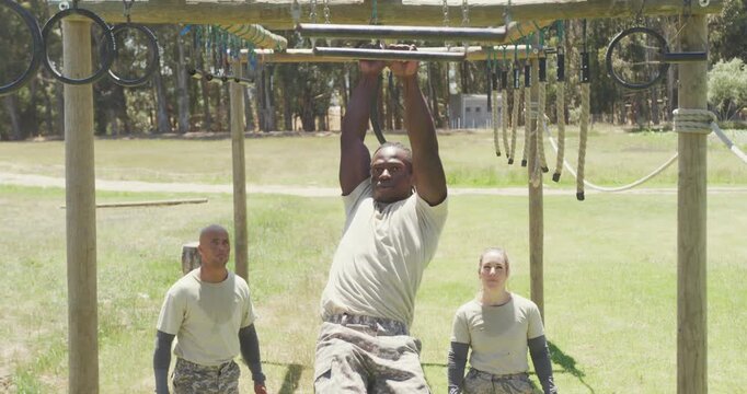 Fit african american male soldier using trapeze bars on army obstacle course