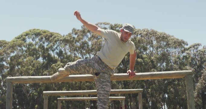 Diverse group of soldiers going over and under hurdles on army obstacle course in the sun