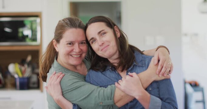 Portrait of caucasian lesbian couple looking at camera, embracing