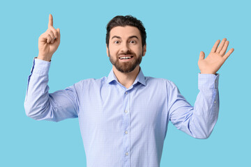 Fototapeta premium Young man pointing up on blue background