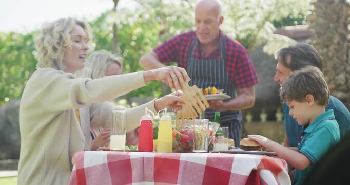 Happy caucasian family having barbecue and talking in garden