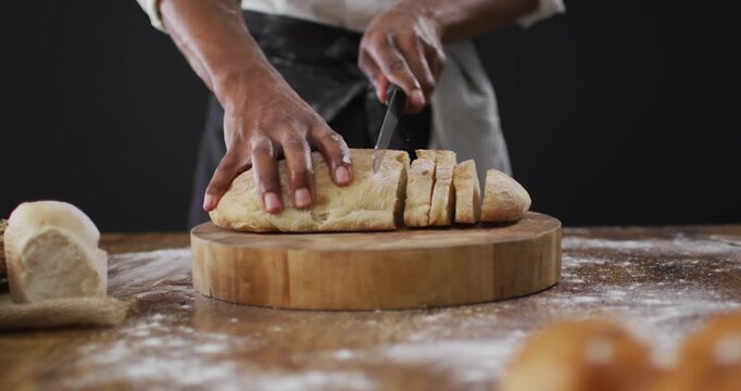 Video of cook cuts the loaf of bread on black background