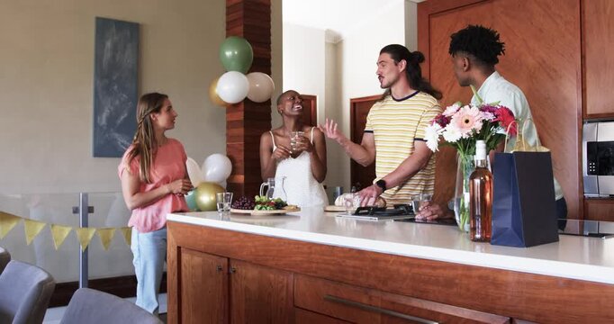 Friends celebrating in kitchen, raising glasses and smiling with joy