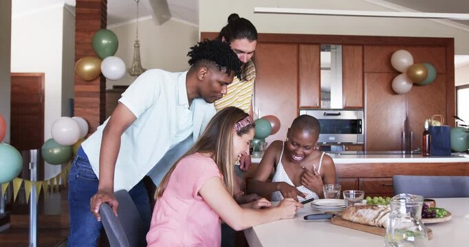 At party, Diverse friends enjoying conversation and laughter around dining table at home
