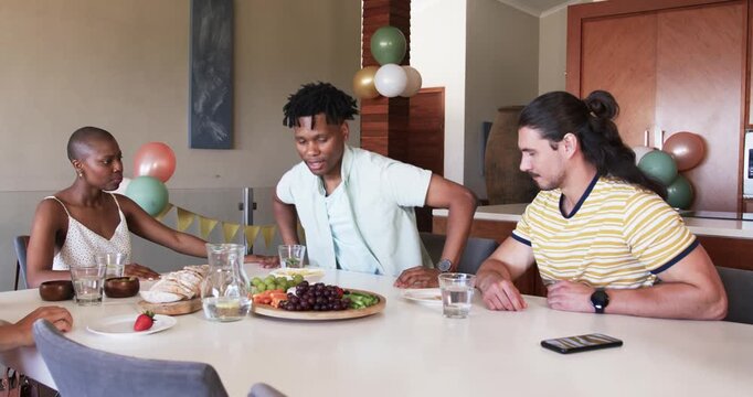 At party, Friends preparing meal together, arranging fruits and bread on dining table