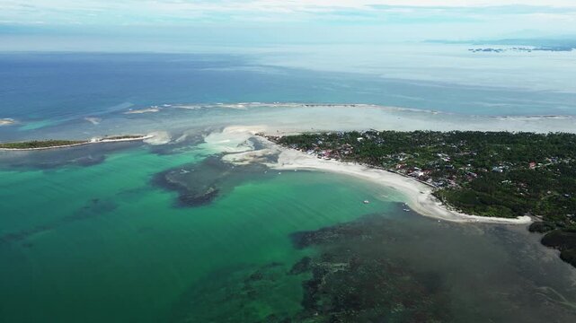 Centered aerial composition capturing island shoreline, palm trees, white sand, and shallow water at Tondol.