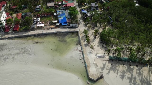 Centered aerial framing the island with surrounding clear water, palm trees, and white sand shoreline.