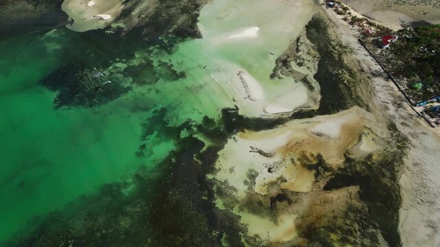 Diagonal wide aerial passing over Tondol islands with crystal clear water blending blue and green tones.