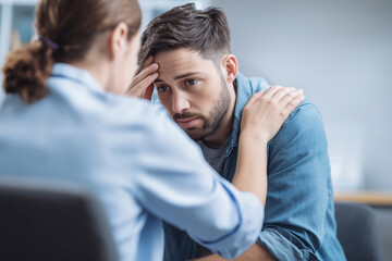 Obraz premium Concerned young man receiving emotional support during therapy session, anxiety counseling, mental health discussion, empathetic communication, stress burnout recovery, psychologist consultation
