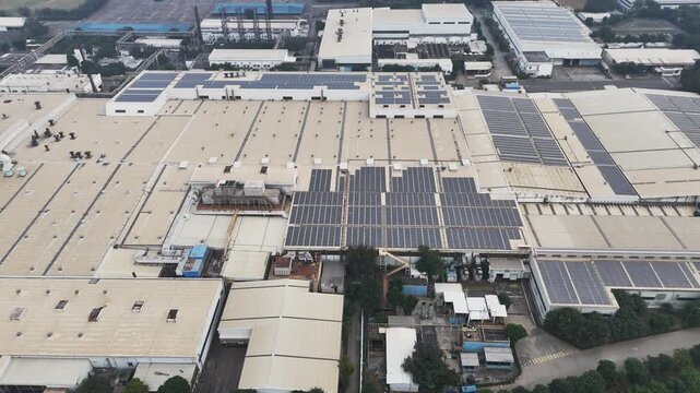 Drone shot of a large factory complex with solar panels bordered by tree-lined roads and traffic corridors, captured under hazy skies that reflect ongoing air quality challenges in Greater Noida.