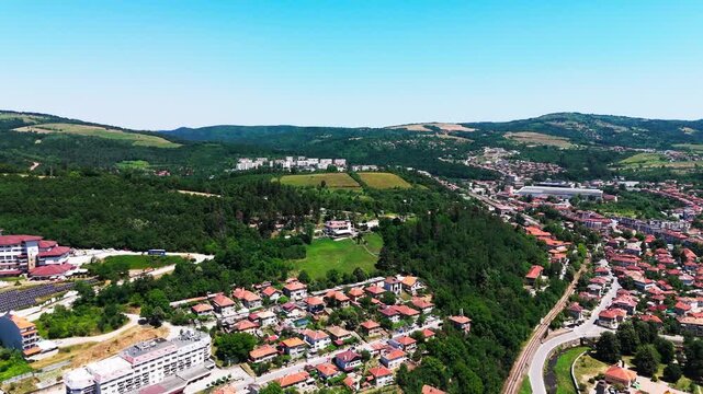 Wide push-in drone shot toward the Brushlyan Complex, revealing an expansive view of Tryavna and its surrounding green hills.