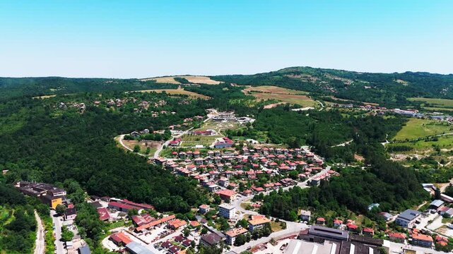 Drone glides over village homes and complexes, revealing forests, fields, and the expansive natural landscape of the Balkan region.