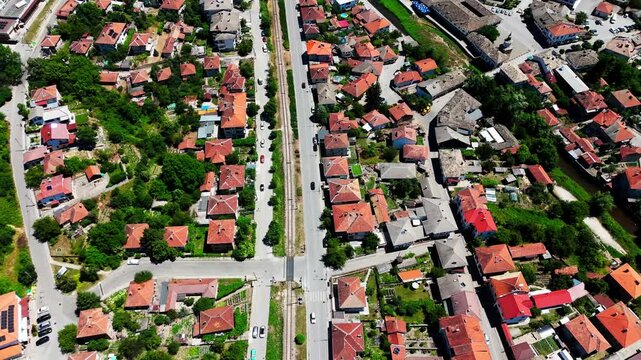 Drone follows a main road through Tryavna, revealing terracotta rooftops, moving cars, and the village layout set in a lush Balkan valley.