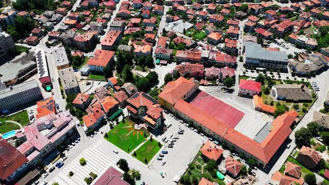 Pan-up drone shot rising from village rooftops to the lush green hills encircling Tryavna.