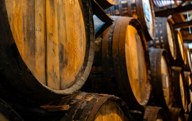 Naklejka premium Rows of wooden oak barrels in a wine cellar.