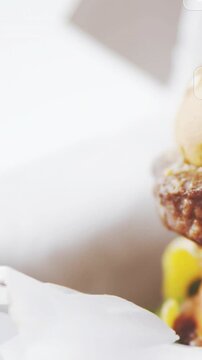 Vertical video: Burger sliding right after social icons popping, cam panning to show white backdrop