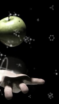 Vertical video: Green apple drifting gently above palm, hand lifting to cradle, molecules drifting
