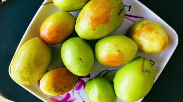 Top view of fresh green and yellow Indian jujube (Ber) fruits served on a white floral plate