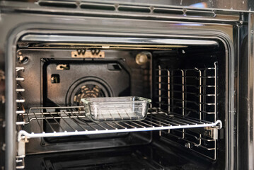Obraz premium Open black electric oven interior with convection fan and metal rack