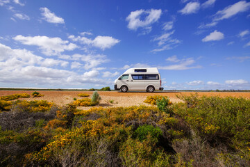 Campervan on coastal road near Cervantes, Western Australia under wide blue sky