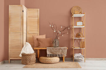 Vase with tree branches and Easter eggs on bench in festive hall