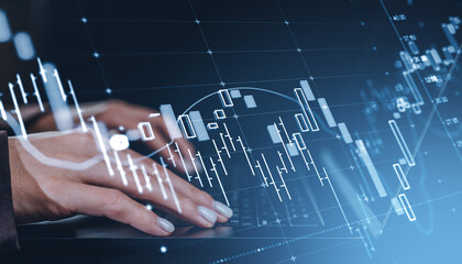 Hands typing on laptop keyboard with financial data charts and candlestick graphs overlayed on...