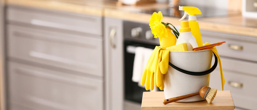 Bucket with cleaning supplies, tools and daffodil flowers on chair at home