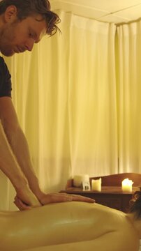 Massage session - master massaging the oiled bare back of his female client