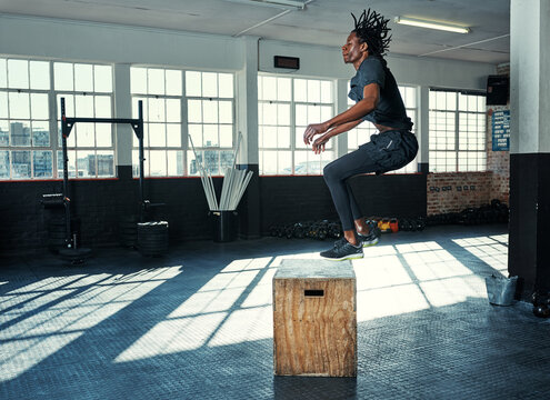 Box, jump and man in gym, active and bodybuilder with balance, fitness or workout routine for health. Athlete, cardio and black person with wooden equipment for exercise, wellness and training