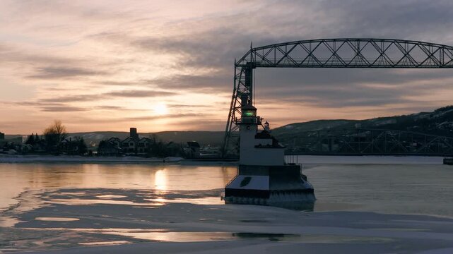 Duluth North Pier Lighthouse and Aerial Lift Bridge at dawn with thick winter frost smoke swirling over the icy waters of the Duluth Ship Canal.