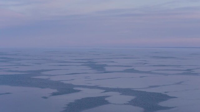 High-angle minimalist aerial view of ice floes and frost patterns on a frozen Lake Superior. Ethereal, cold blue tones and natural textures