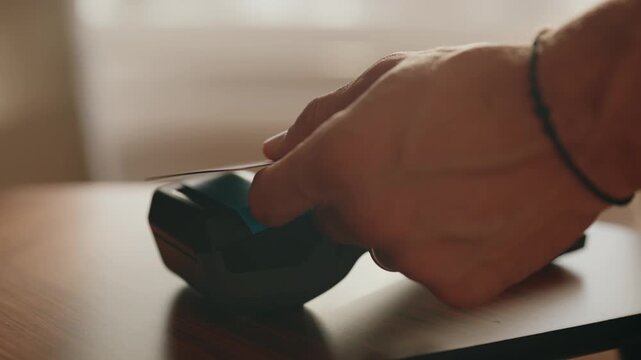 Close-up of a customer's hand paying with a credit card using a POS terminal inside a shop, demonstrating the ease of modern electronic and contactless transactions in commerce
