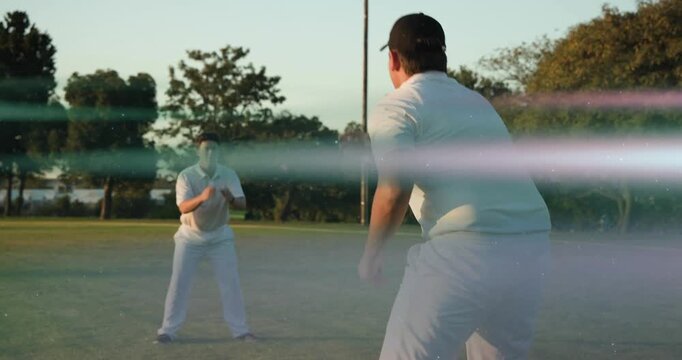 Bowler starting delivery releasing ball, fielder tracking catching in sports, flares obscuring view