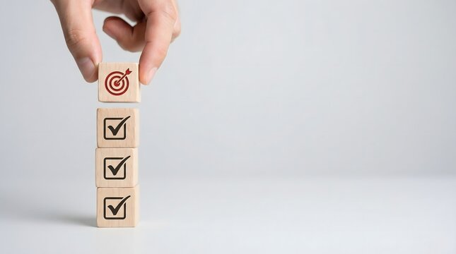 hand placing wooden block with target symbol on stack of blocks with checkmarks