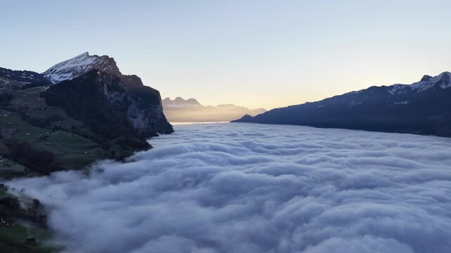 Walensee Switzerland drone above sea of clouds with alpine mountains at sunrise, soft morning light, calm atmosphere,peaceful European nature landscape.