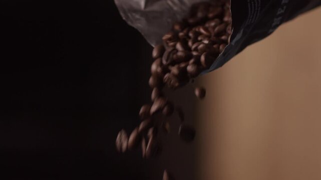 Close-up footage of roasted coffee beans being poured from a bag, creating a smooth, natural and visually engaging motion. The falling coffee beans fill the frame, highlighting rich texture, deep brow