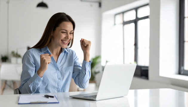 Happy woman success office laptop business professional achievement motivation celebration career. young woman blue shirt celebrates quietly with small fist pump while looking her laptop