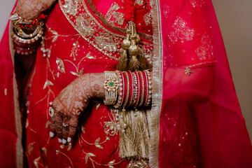Obraz premium Exquisite Indian Wedding Dress Detail: Embroidered Fabric, Hennaed Hands, and Traditional Bangles in Vivid Red and Gold – Capturing Cultural Richness