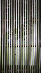Obraz premium A close-up view of multiple vertical metal tubes arranged closely together, reflecting light and showcasing their textured surfaces, in a neat and organized pattern.