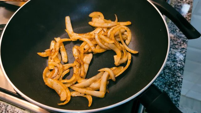food preparation: brown sliced onions being fried on black cast iron wok 