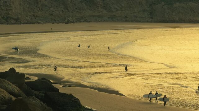 Sunset at Imsouane beach in Morocco with surfers surfing waves, cinematic ocean travel scene with calm evening light