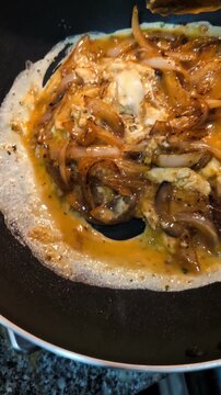 Healthy and nutritional lifestyle: Healthy breakfast preparation: fried brown onions with scrambled eggs being mixed on black cast iron wok